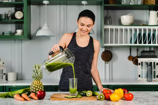 A woman pouring a green smoothie into a glass