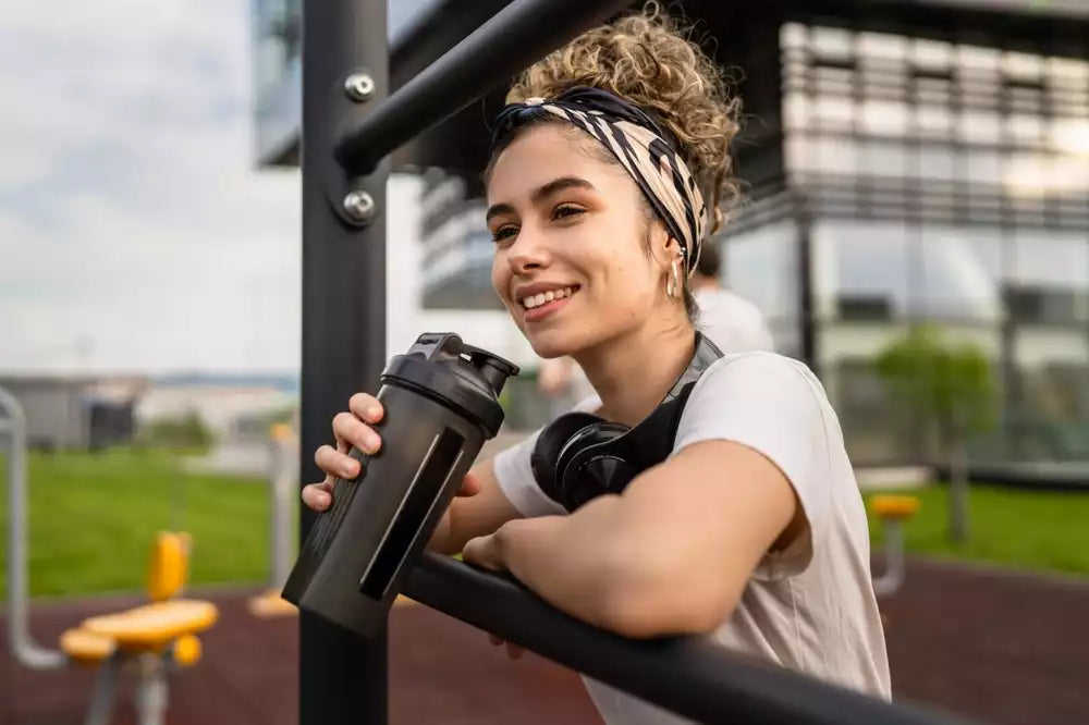 A woman drinking a protein shake outside