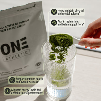 Green powder being added to a glass with One Athletic packaging in the background