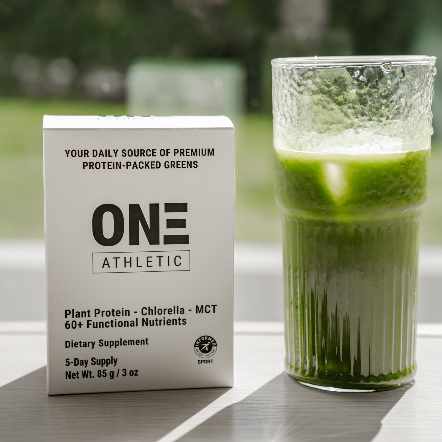 Front view of ON3 Athletic box next to glass of ON3 Athletic